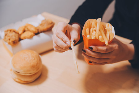 Asian woman holding french fries and eating happily in restaurantの写真素材