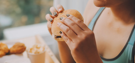 Binge eating disorder concept with woman eating fast food burger, fired chicken , donuts and dessertsの写真素材