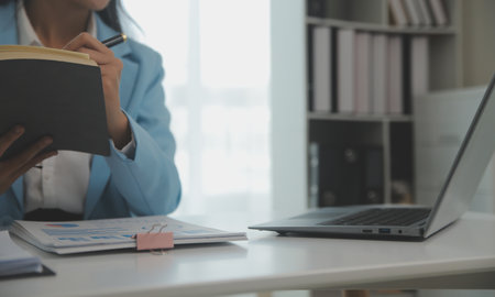 Charming Young asian businesswoman sitting on laptop computer in the office, making report...