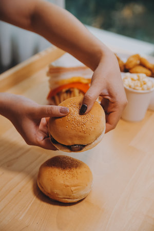 Binge eating disorder concept with woman eating fast food burger, fired chicken , donuts and dessertsの写真素材
