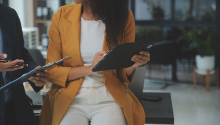 Entrepreneur Asian businessman and businesswoman discussing new business project in tablet in modern Meeting In Modern Office, Asian business casual concept.の写真素材