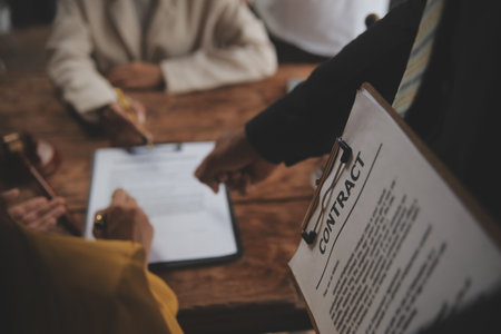 Business and lawyers discussing contract papers with brass scale on desk in office. Law, legal services, advice, justice and law concept picture with film grain effectの写真素材