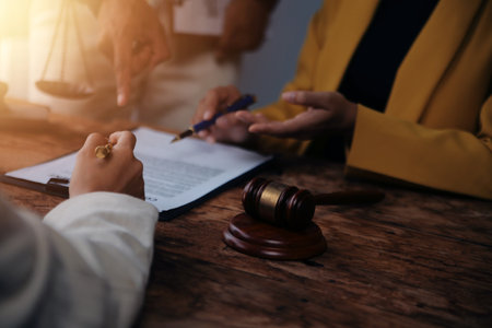 Business and lawyers discussing contract papers with brass scale on desk in office. Law, legal services, advice, justice and law concept picture with film grain effectの写真素材