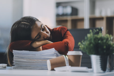 The business lady and the employee take a nap while working on the office desk. Working women are exhausted and sleeping on the tableの写真素材