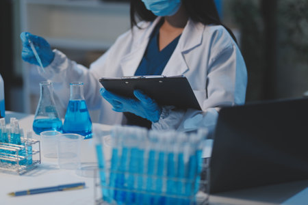 Group of dedicated scientist conduct chemical experiment in medical laboratory, carefully drop precise amount of liquid from pipette into test tube for vaccine drug or antibiotic development. Neotericの写真素材