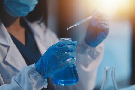 Group of dedicated scientist conduct chemical experiment in medical laboratory, carefully drop precise amount of liquid from pipette into test tube for vaccine drug or antibiotic development. Neotericの写真素材