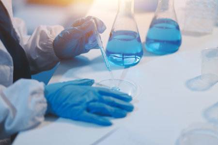 Group of dedicated scientist conduct chemical experiment in medical laboratory, carefully drop precise amount of liquid from pipette into test tube for vaccine drug or antibiotic development. Neotericの写真素材