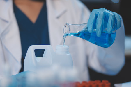 Group of dedicated scientist conduct chemical experiment in medical laboratory, carefully drop precise amount of liquid from pipette into test tube for vaccine drug or antibiotic development. Neotericの写真素材
