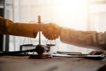 Lawyer shaking hands with a client making about documents, contracts, agreements, cooperation agreements with a female client at the lawyer's desk and a hammer at the table.の写真素材