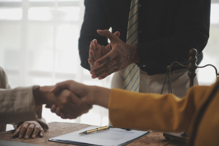 Lawyer shaking hands with a client making about documents, contracts, agreements, cooperation agreements with a female client at the lawyer's desk and a hammer at the table.の写真素材