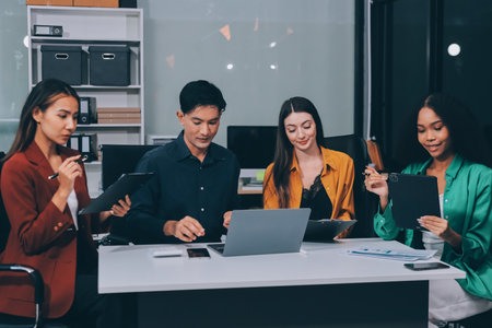 Young corporate employees sitting in office looking at laptop screen reading good news excited happy team diverse people celebrating victory win command success excellent result professional teamworkの写真素材