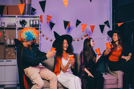 Joyful office Halloween party with coworkers in costumes, celebrating with drinks and laughter, fostering teamwork and festive spiritの写真素材