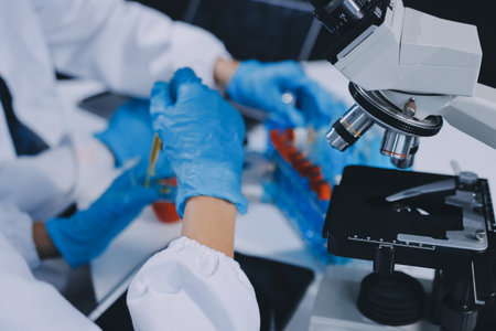 Scientist using microscope in laboratory. Close-up of a researcher's hands adjusting a modern microscope in a lab setting. Science conceptの写真素材