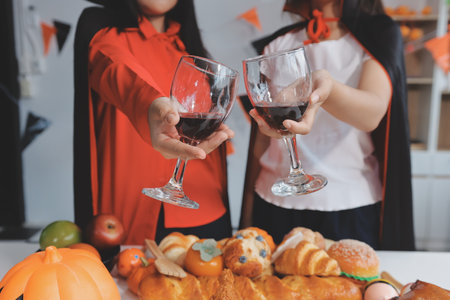 friendship, holiday and people concept - group of happy smiling friends in halloween costumes of vampire, devil, witch and cheetah at home partyの写真素材