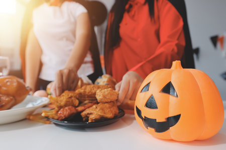 friendship, holiday and people concept - group of happy smiling friends in halloween costumes of vampire, devil, witch and cheetah at home partyの写真素材