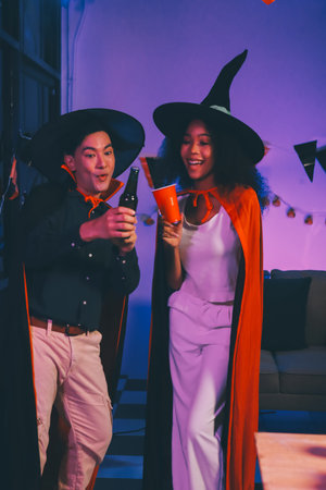 Joyful office Halloween party with coworkers in costumes, celebrating with drinks and laughter,...