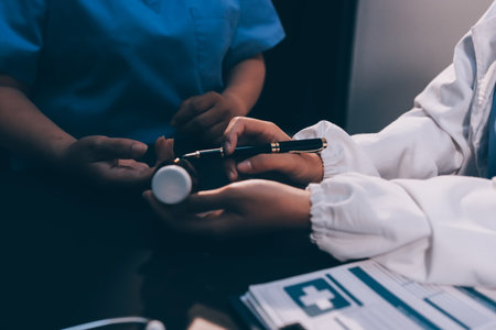 Senior woman holding medicine bottle with nurse using laptop at homeの写真素材