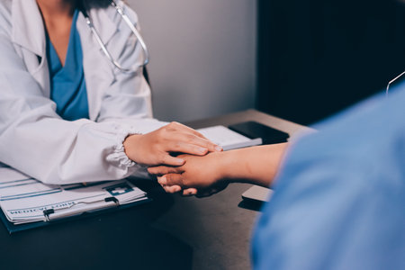 Kind male doctor wearing white coat consulting elder senior female patient holding hand of older...