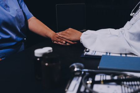 Kind male doctor wearing white coat consulting elder senior female patient holding hand of older...