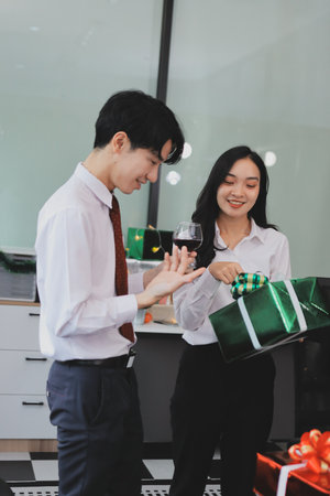 full length view of a group of business team wearing red Santa hat and exchange gift box together in the office for Christmas.の写真素材