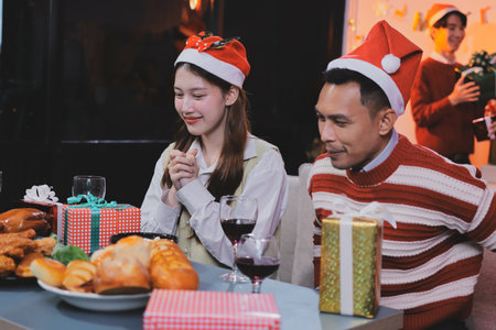 Group of happy Asian friends celebrating Christmas and decorate the Christmas tree indoors. Beauty woman with Christmas Gifts. New Year party. Woman hands decorate Christmas tree red ball, bauble.の写真素材