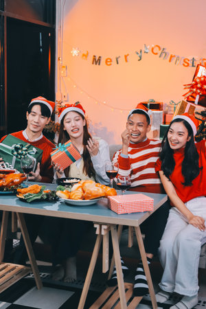 Group of happy Asian friends celebrating Christmas and decorate the Christmas tree indoors. Beauty woman with Christmas Gifts. New Year party. Woman hands decorate Christmas tree red ball, bauble.の写真素材