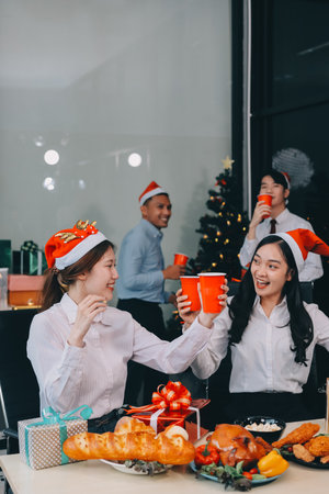 full length view of a group of business team wearing red Santa hat and exchange gift box together in the office for Christmas.の写真素材