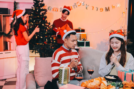 Group of happy Asian friends celebrating Christmas and decorate the Christmas tree indoors. Beauty woman with Christmas Gifts. New Year party. Woman hands decorate Christmas tree red ball, bauble.の写真素材
