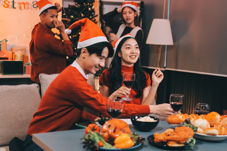 Group of young Asian man and women as friends having fun at a New Year's celebration, holding gift boxes standing by Christmas tree decoration, midnight countdown Party at home with holiday season.の写真素材