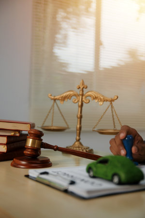 Judge gavel and miniature car symbolize auction or court case against driver who has accident and receiving vehicle insurance payment be on table in front of hands of lawyers. Selective focusの写真素材