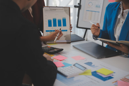 Meeting with business partners to discuss financial advisors to analyze market growth charts in business reports and plan investment strategies.の写真素材