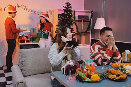 Group of happy Asian friends celebrating Christmas and decorate the Christmas tree indoors. Beauty woman with Christmas Gifts. New Year party. Woman hands decorate Christmas tree red ball, bauble.の写真素材