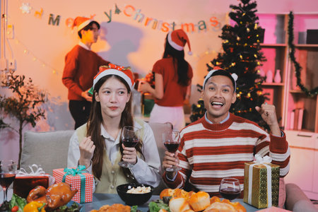 Group of happy Asian friends celebrating Christmas and decorate the Christmas tree indoors. Beauty woman with Christmas Gifts. New Year party. Woman hands decorate Christmas tree red ball, bauble.の写真素材