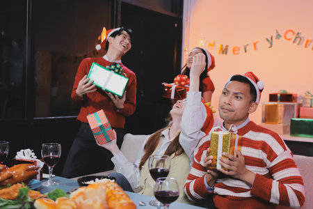 Group of happy Asian friends celebrating Christmas and decorate the Christmas tree indoors. Beauty woman with Christmas Gifts. New Year party. Woman hands decorate Christmas tree red ball, bauble.の写真素材