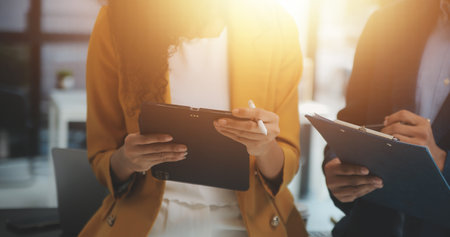 Entrepreneur Asian businessman and businesswoman discussing new business project in tablet in modern Meeting In Modern Office, Asian business casual concept.の写真素材