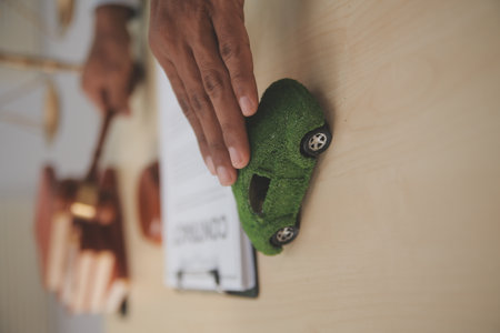 Judge gavel and miniature car symbolize auction or court case against driver who has accident and receiving vehicle insurance payment be on table in front of hands of lawyers. Selective focusの写真素材
