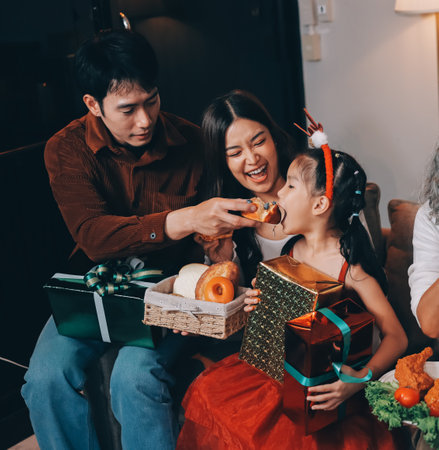 Portrait of Asian family exchanging presents during christmas at home. Attractive happy people holding gift box, celebrate holiday thanksgiving, xmas eve tradition in living room in house together.の写真素材
