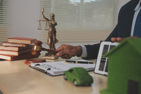 Judge gavel and miniature car symbolize auction or court case against driver who has accident and receiving vehicle insurance payment be on table in front of hands of lawyers. Selective focusの写真素材