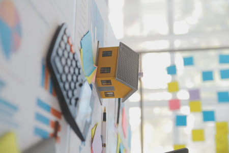 Wooden table with laptop, house keys Clipboard with pen, house model and green tree calculator, real estate concept. close up picturesの写真素材