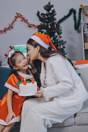 Merry Christmas and Happy Holidays. Cheerful mom and her cute daughter girl exchanging gifts. Parent and little child having fun near tree indoors.の写真素材