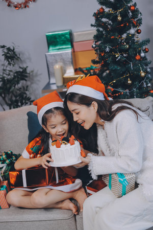 Merry Christmas and Happy Holidays. Cheerful mom and her cute daughter girl exchanging gifts. Parent and little child having fun near tree indoors.の写真素材