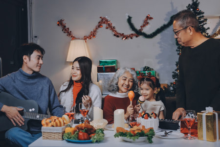 Multi-Generation Family Celebrate Christmas At Home Wearing Santa Hats And Antlers Opening Presentsの写真素材