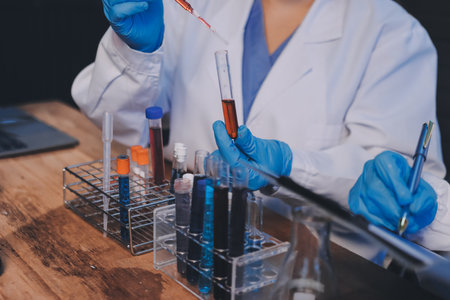 Blood test in the laboratory. Laboratory assistant working with the dispenser. Vacuum tubes with blood.の写真素材