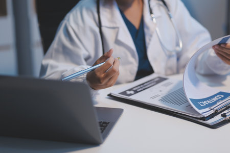 Doctor sitting at desk and writing a prescription for her patientの写真素材