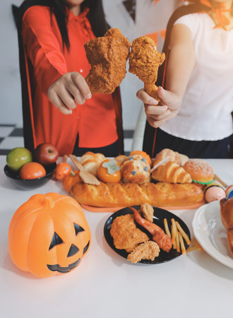 friendship, holiday and people concept - group of happy smiling friends in halloween costumes of vampire, devil, witch and cheetah at home partyの写真素材