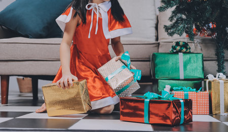 Christmas holidays concept. Happy magic little girl opens a gift box. Child is happy with a New Year's gift. The background is Christmas tree. The concept of Christmas and New Year. High quality photoの写真素材