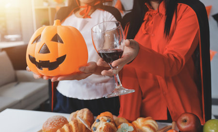 friendship, holiday and people concept - group of happy smiling friends in halloween costumes of vampire, devil, witch and cheetah at home partyの写真素材