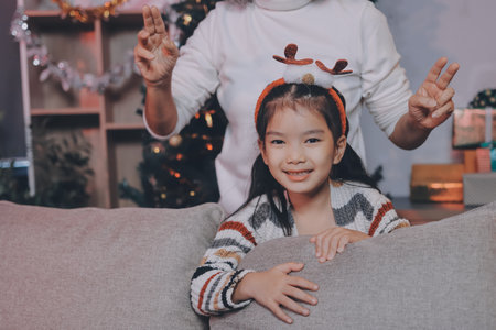 Happy family on Christmas morning. Affectionate grandmother and cheerful granddaughter open a holiday gift together at homeの写真素材