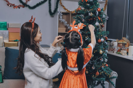 Merry Christmas and Happy Holidays. Cheerful mom and her cute daughter girl exchanging gifts. Parent and little child having fun near tree indoors.の写真素材