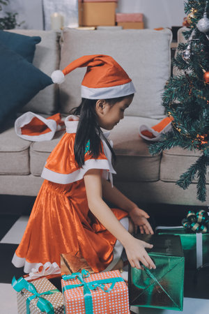 Christmas holidays concept. Happy magic little girl opens a gift box. Child is happy with a New Year's gift. The background is Christmas tree. The concept of Christmas and New Year. High quality photoの写真素材